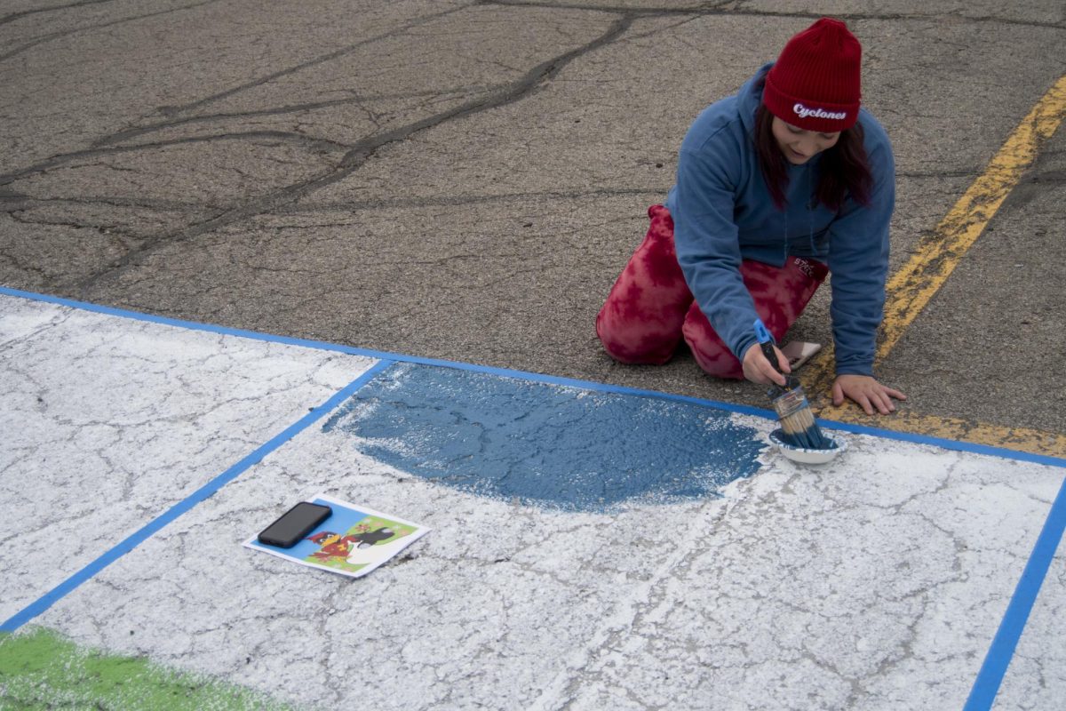 Allison Scaletta, a member of the Cardinal Tap Club, begins to paint her club’s square during The Painting of Victory Lane event at the beginning of Iowa State’s Homecoming week on Sunday, Oct. 29, 2023, outside the Alumni Center in Ames, Iowa.
