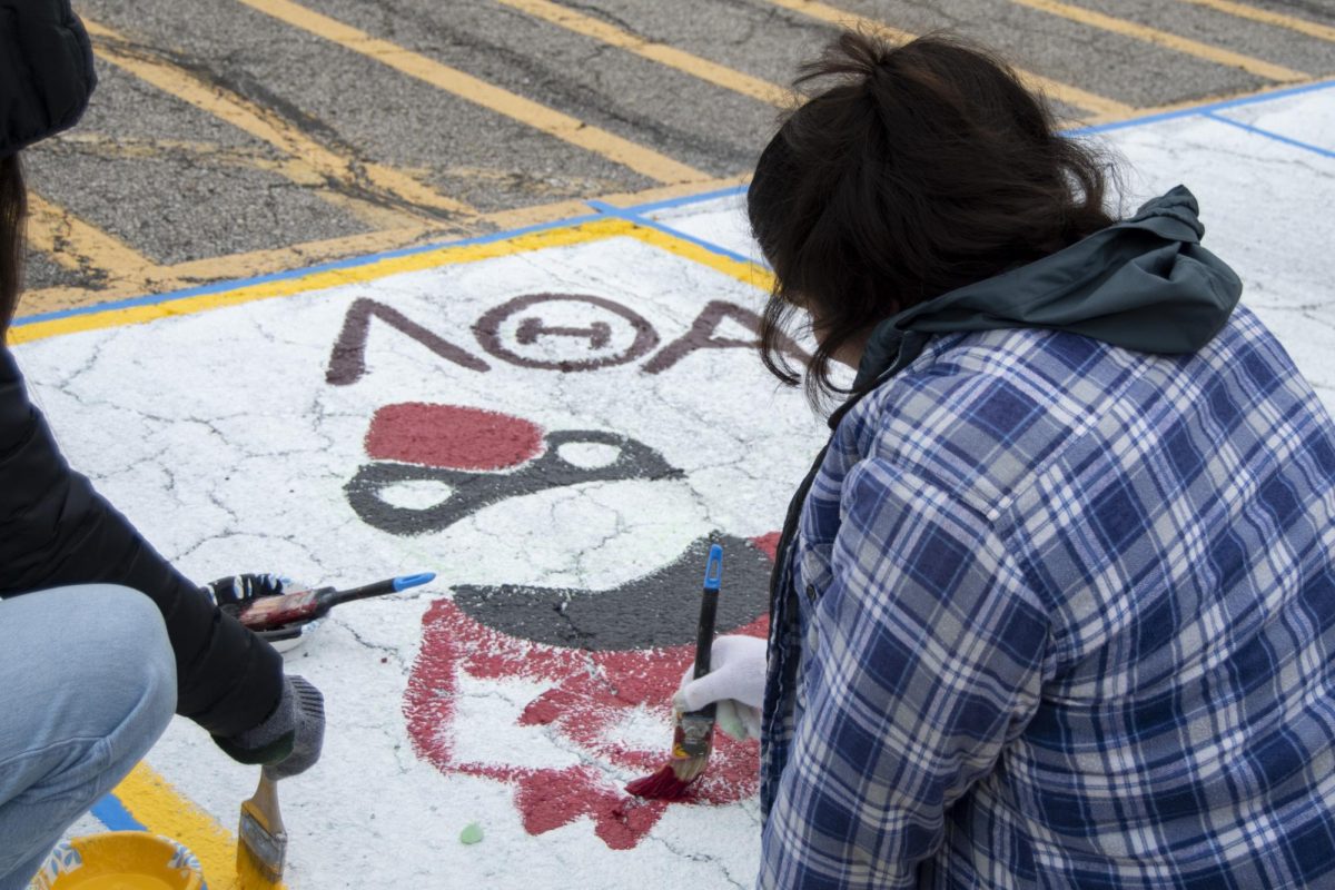Members of the Lambda Theta Alpha Latin Sorority, Inc. paint Cy the Cardinal in their square during The Painting of Victory Lane event at the beginning of Iowa State’s Homecoming week on Sunday, Oct. 29, 2023, outside the Alumni Center in Ames, Iowa.
