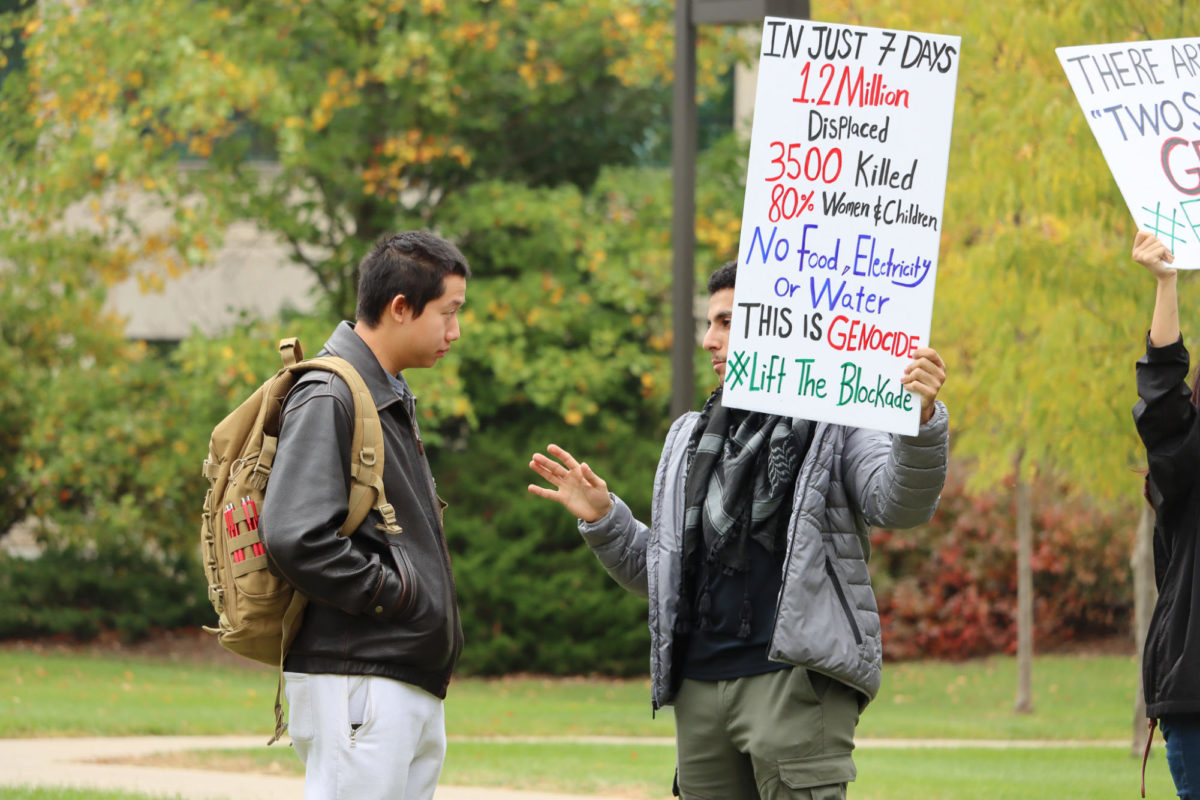 Mohammad (right), a senior at Iowa State, explains the gathering to a bystander of the Stand with Gaza gathering, outside Parks Library, on Oct. 19, 2023.