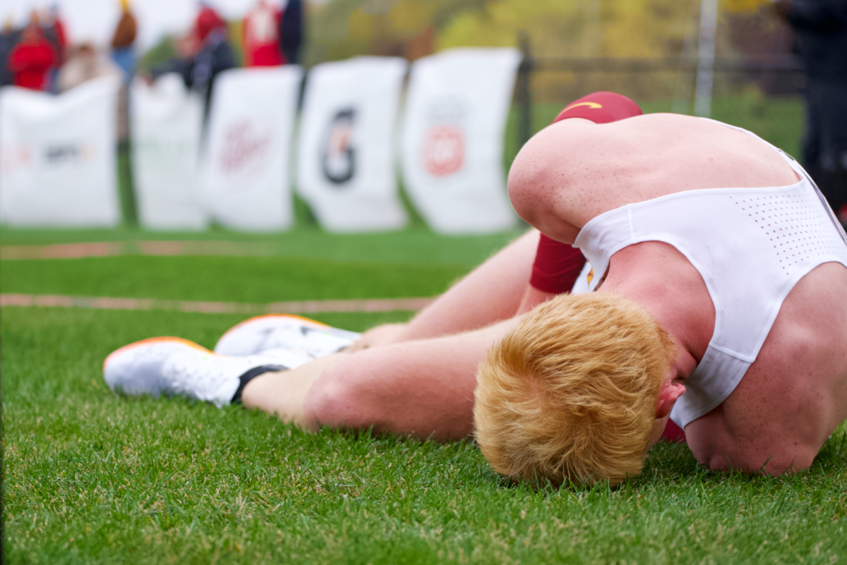 Quinton Orr falls to the ground in pain after a challenging finish for the Big 12 Men’s Cross Country Championship on Oct. 28, 2023