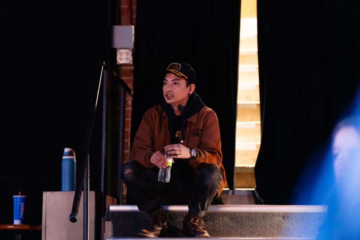 Asia Samson sits on the back steps of the Maintenance Shop while listening to Iowa State freshman design student Lauren "Lo" Wilinski opens for Spoken Word Night, Memorial Union, Nov. 14, 2023.