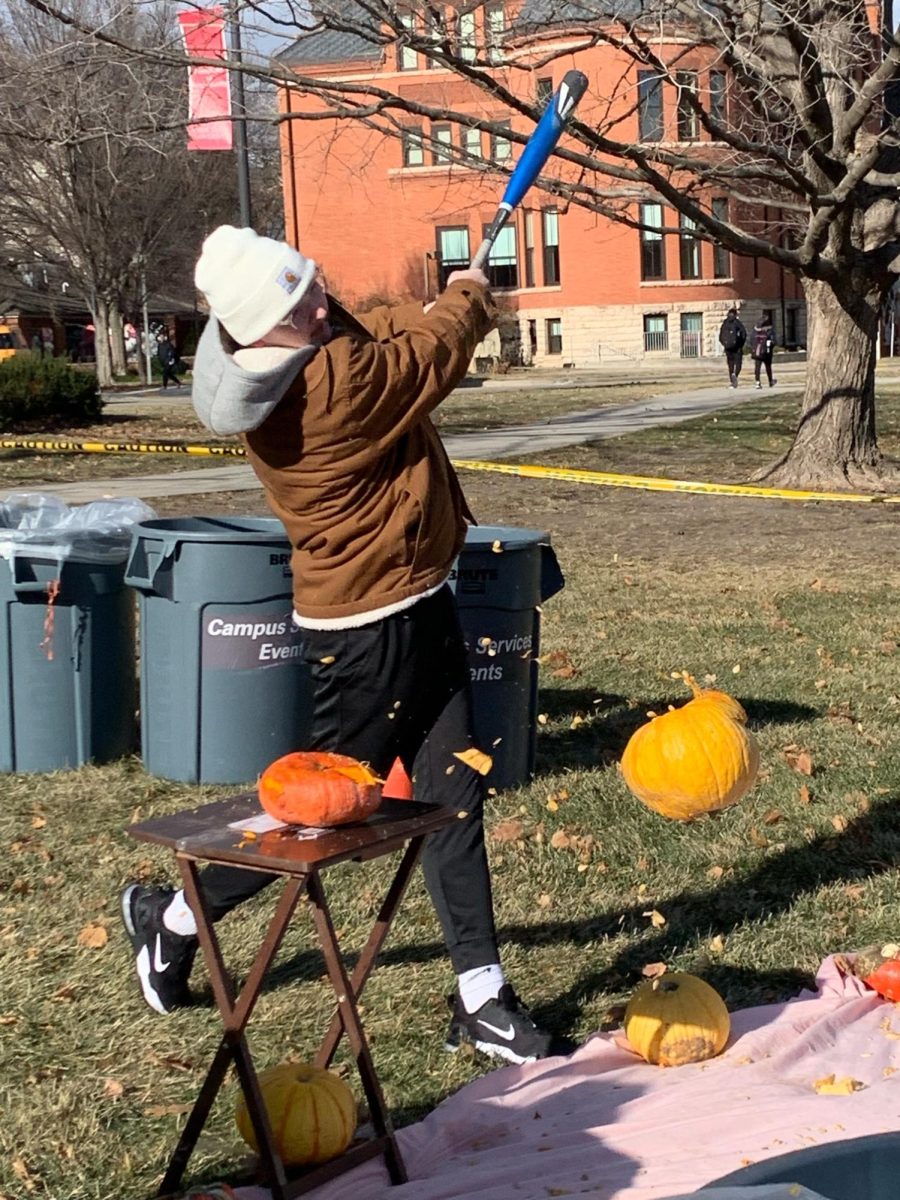 A student smashes a pumpkin during a pumpkin smashing event.
