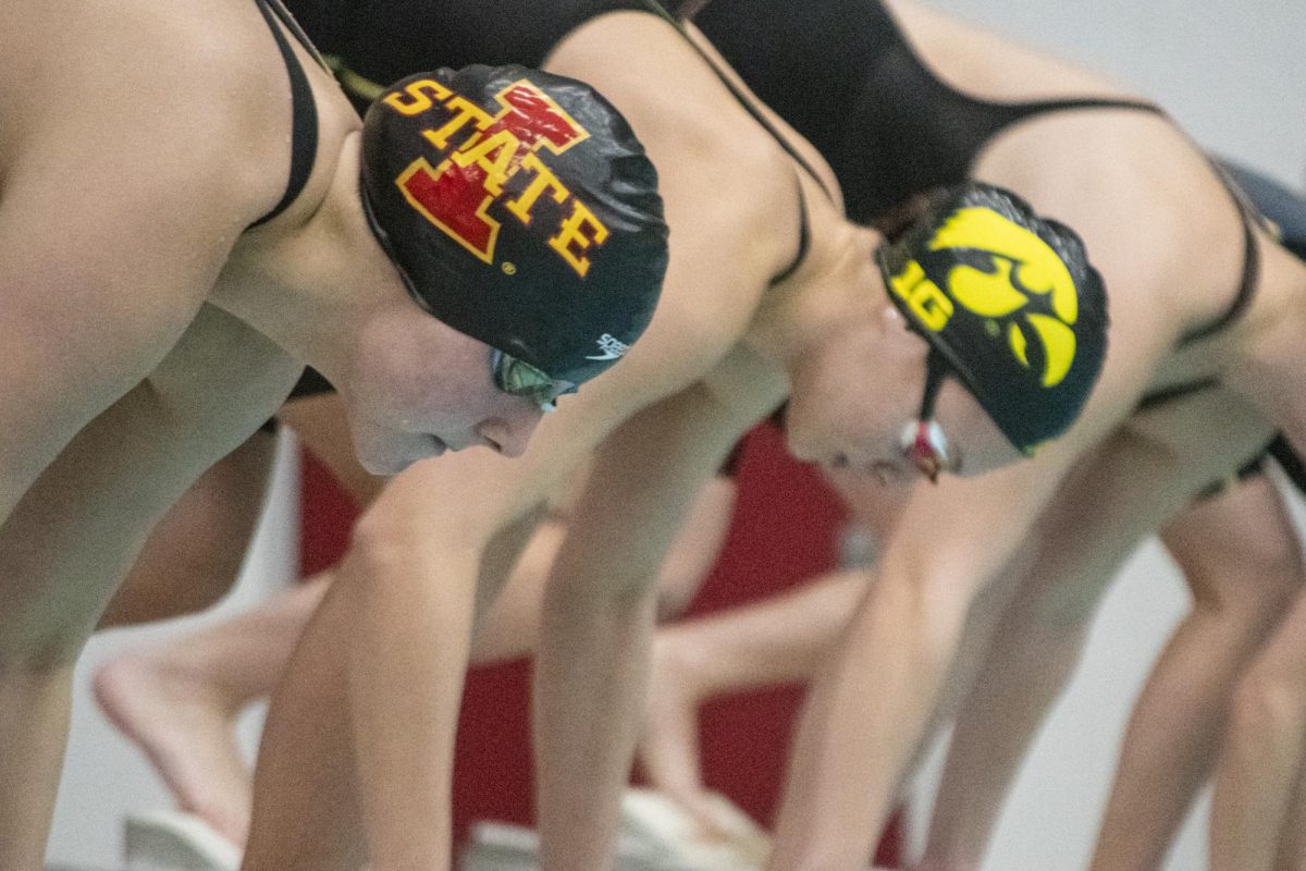 Iowa State and Iowa swim team members prepare to launch off their blocks during the annual Cy-Hawk meet on Friday, Dec. 8, 2023, at Beyer Hall in Ames, Iowa.