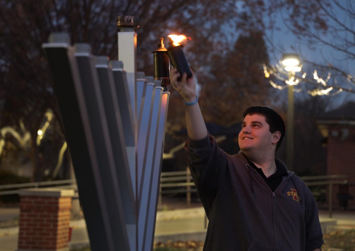 Anthony David, a board member of Chabad ISU, lights the menorah outside Parks Library on Thursday, Dec. 7, 2023. Tonight is the first night of Hanukkah. 