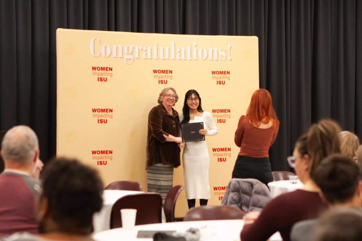 Sue Cloud presents Mia Kawamitsu her award as one of the 2024 Women Impacting ISU Honorees at the 2024 Women Impacting ISU Calendar Unveiling at the Iowa State University Memorial Union on Jan. 17, 2024.