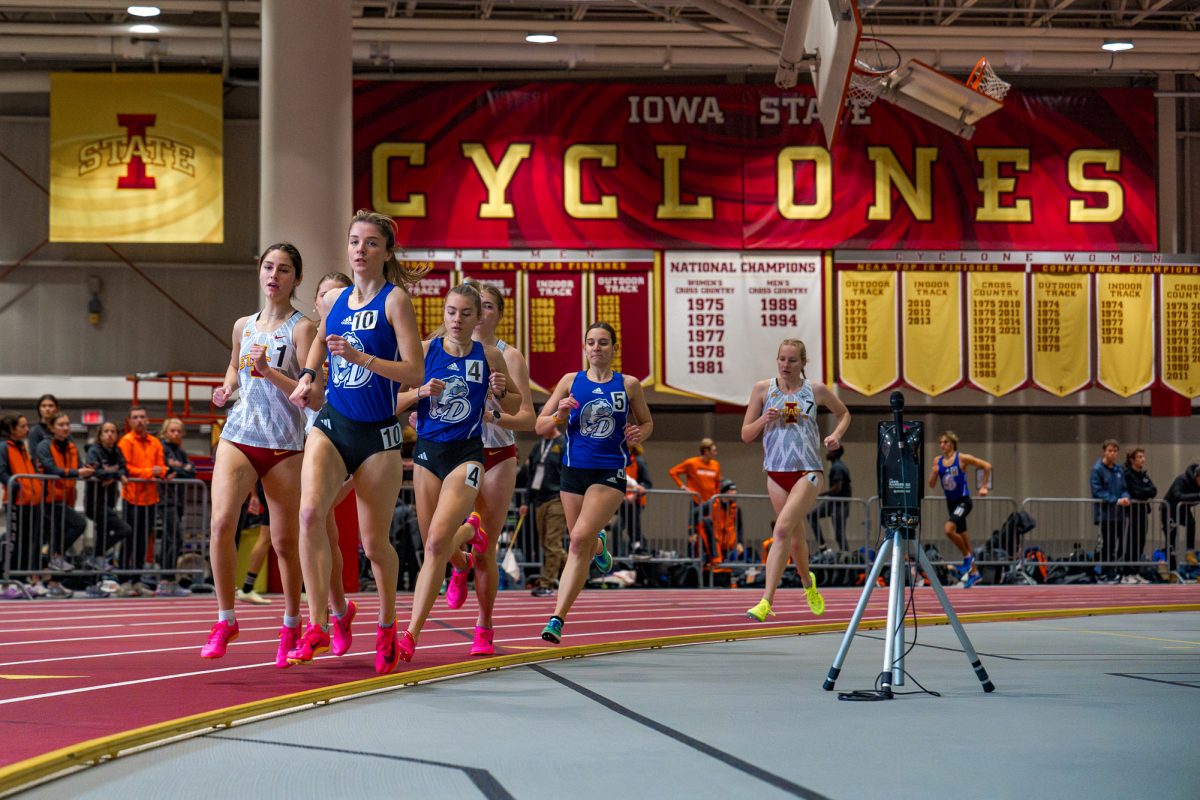 Racers for the womens 1 mile run bunch together as they make a turn during the 2024 Cyclone Open in the Leid Recreational center on Jan. 19, 2024.