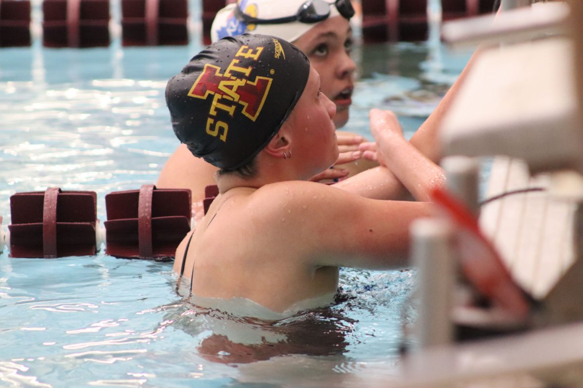 An Iowa State swimmer finishes her race and high fives a Kansas swimmer in the lane next to her at the Iowa State vs. Kansas swim and diving meet at Beyer Hall on Feb. 9, 2024. 