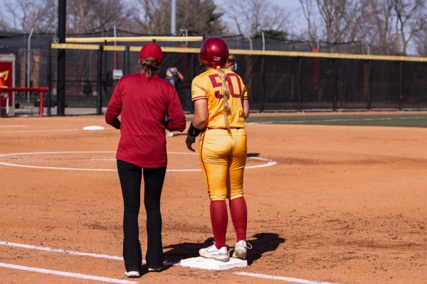 Ashley Minor and her coach talk at first base during the Iowa State vs. DePaul softball game at Cyclones Sports Complex, April 9, 2024.