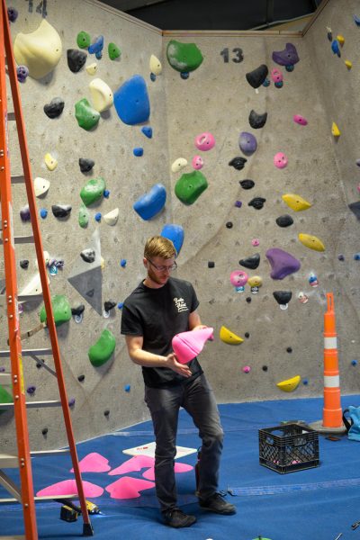 Brian Doscher, the owner or Bluestem Boulders, sets routes on a rock climbing wall. Photo by Jeremiah Martin.