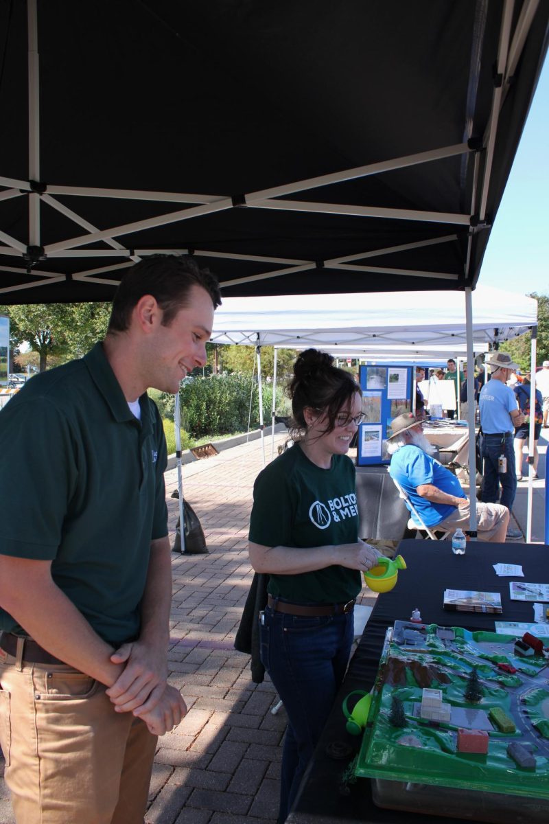 Outside of Ames City Hall, Reese Hansen (Left) and Jessica Fisher (Right), employees of Bolton and Menk, demonstrate their model of the impact of flooding at Ames EcoFair, Sept. 28, 2024.