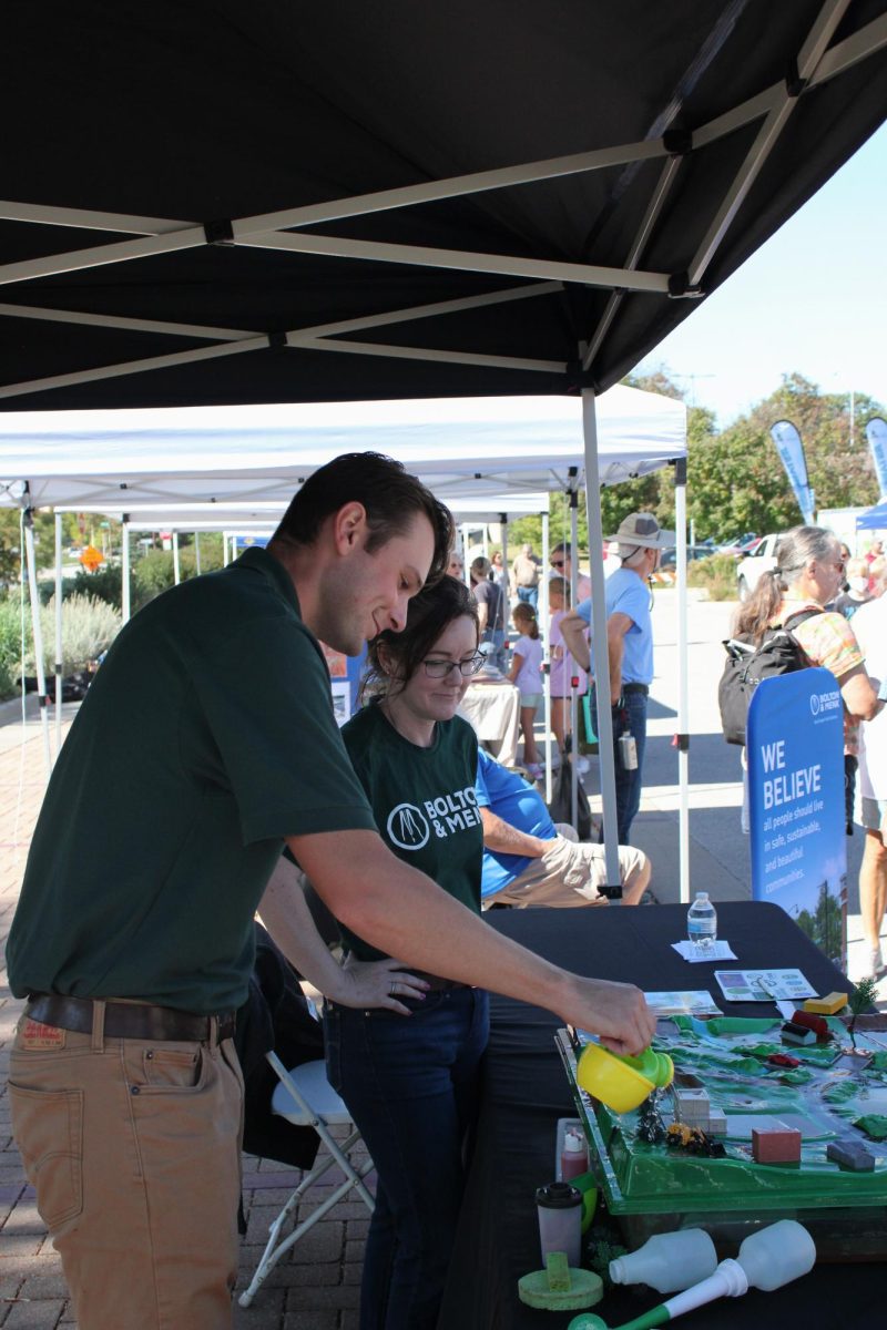 Representing Bolton and Menk, Reese Hansen (Left) and Jessica Fisher (Right) demonstrate their model that represents the impact of flooding from rainfall at the EcoFair, located outside Ames City Hall, Sept. 28, 2024.