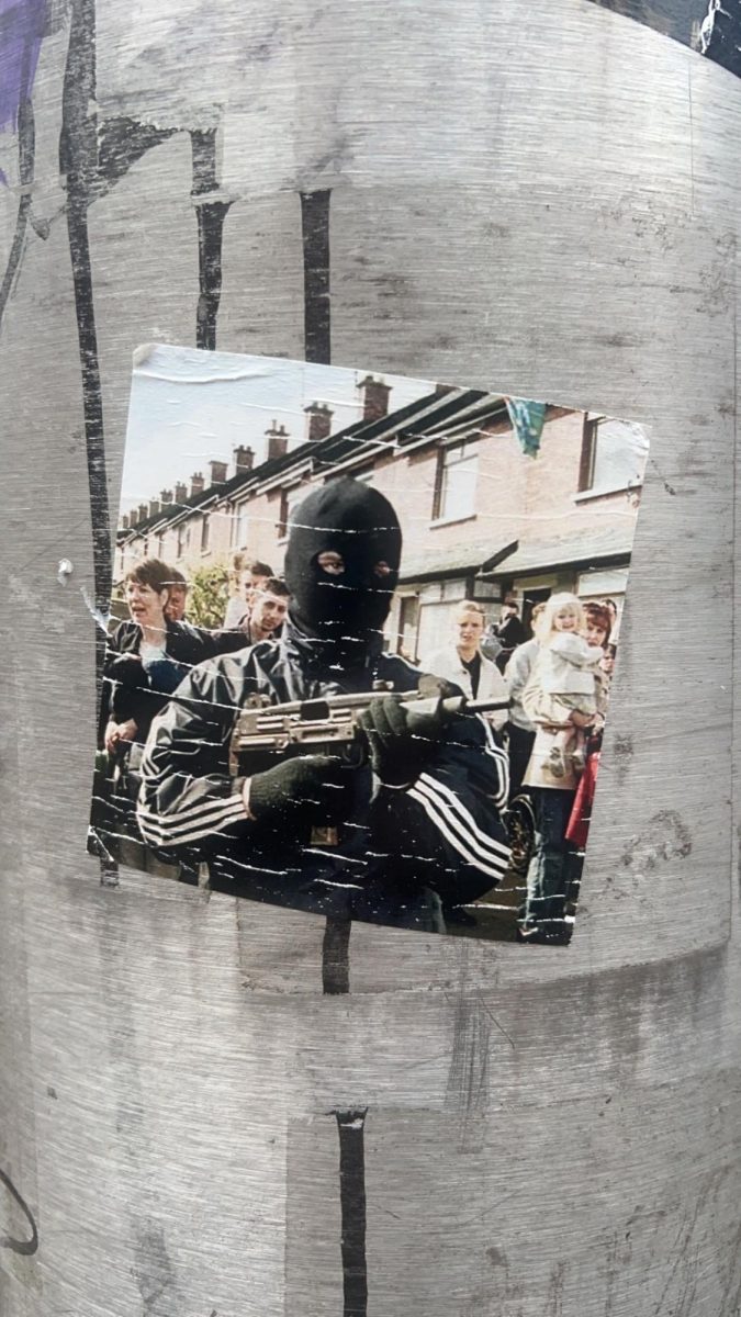 A sticker of a man in a balaclava holding a gun. Photographed in Belfast, Northern Ireland. 