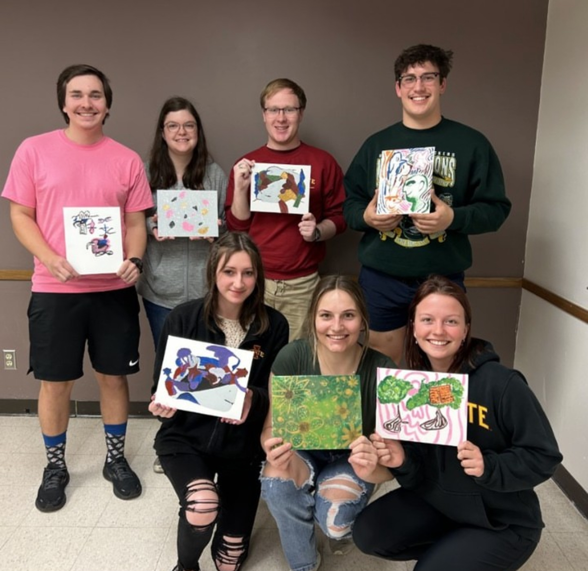 Members of NAMI on Campus pose for a photo with stress relief coloring pages. 