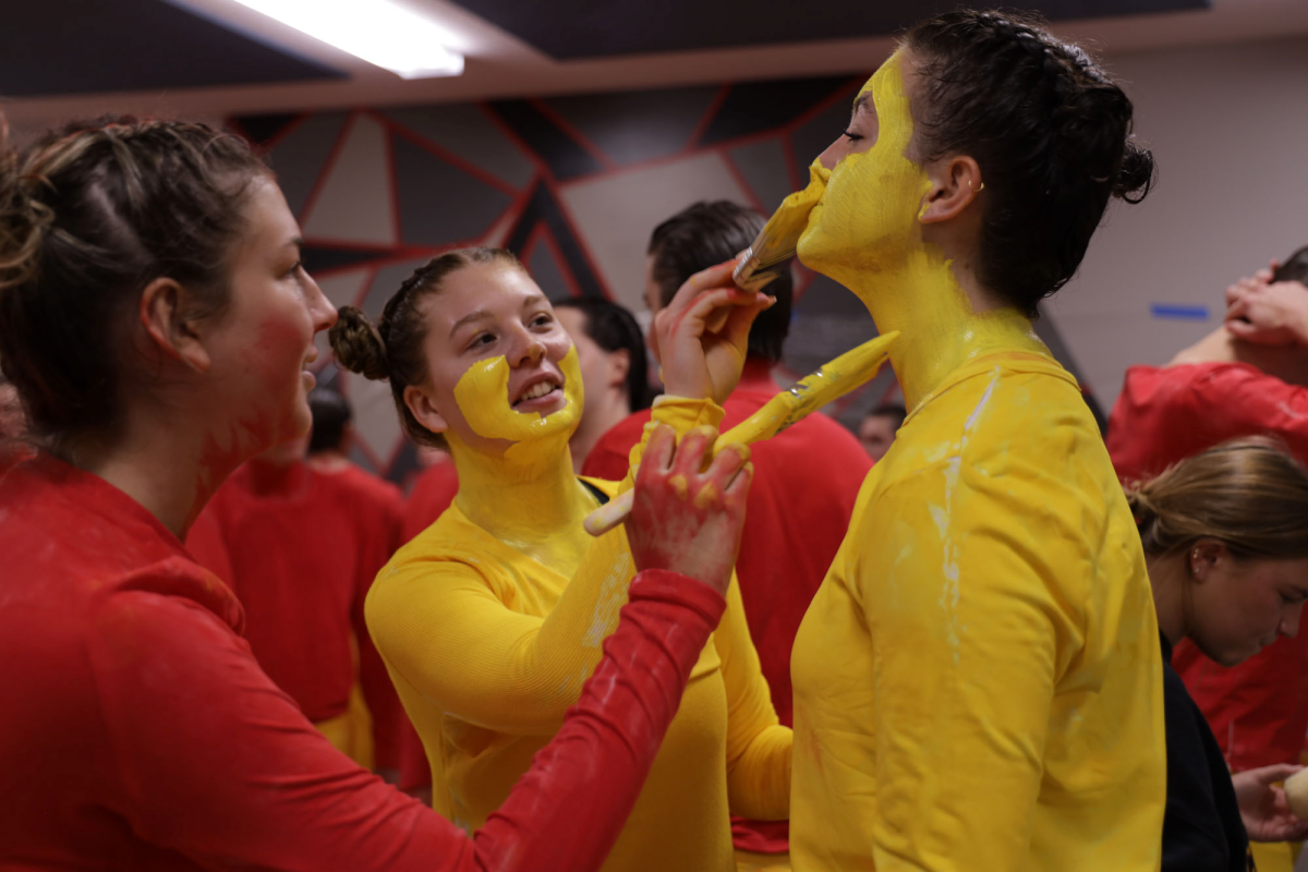 Olivia Judge is painted by Jadyn Renken and Niccola Barges. Members of "Cy Goes Back to the Future" prepare for the Second Cuts of Yell Like Hell on Thursday, Oct. 31, 2024. Teams that make it past First Cuts paint themselves as their characters for the next two rounds.