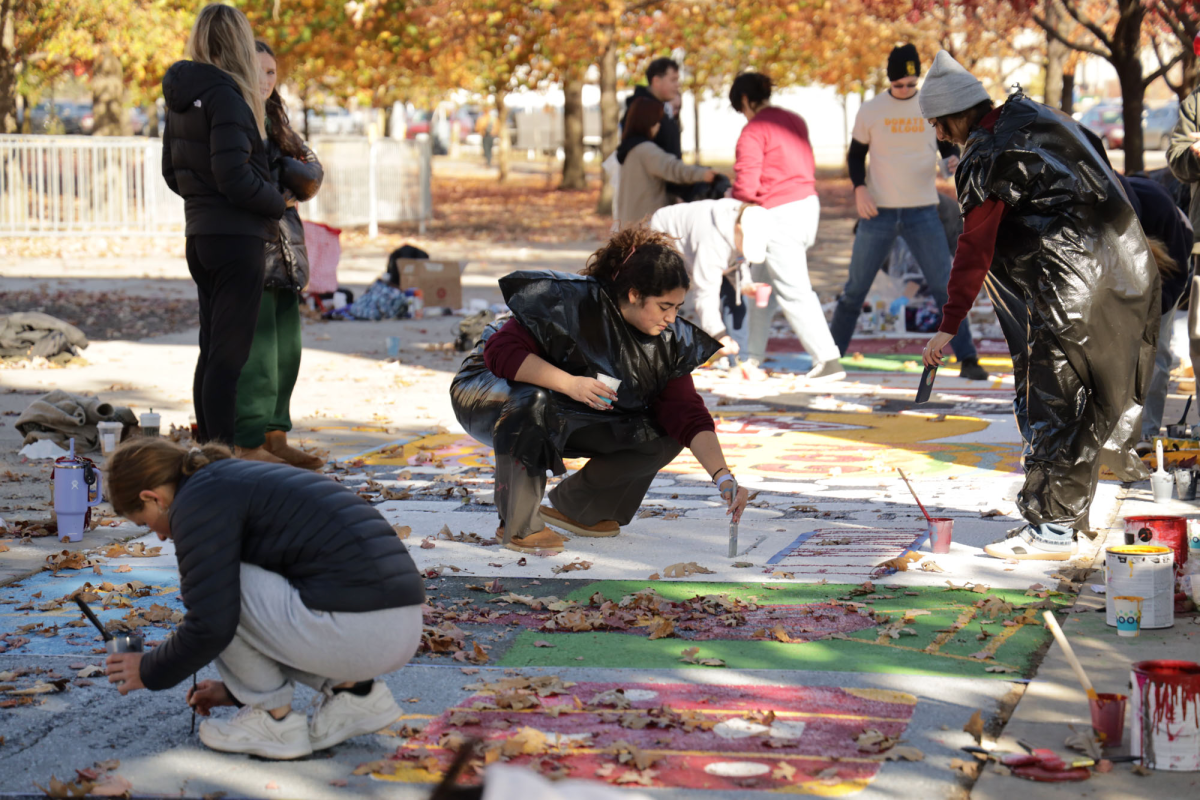 Members of Lambda Theta Alpha wear trashbags while painting their square. Members of more than 20 student organizations painted squares on "Victory Lane" on Sunday, Oct. 27, 2024. Gabrielle Townsend, a member of the Student Alumni Leadership Council, said, "It's a really fun tradition we've had for a long time." Victory Lane was moved closer to Jack Trice Stadium this year, in hopes of making it more accessible to fans attending the Homecoming game.