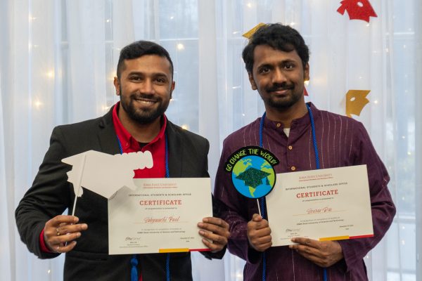 Iowa State ISSO graduates Sabyasachi Paul (L) and Sourav Das (R) proudly take photos with graduate props and their ISSO certificates in the Campanile Room at the Memorial Union, Ames, Iowa, Dec. 12, 2024.