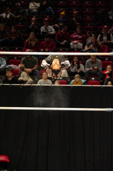 Paige Wills flys to the top bar while competing against Arizona State University in uneven bars, Jan. 31, 2025, Hilton Coliseum, Ames, Iowa.