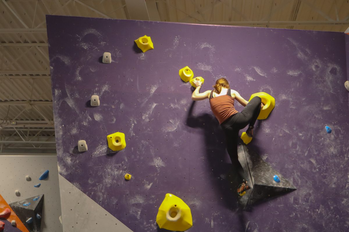 Iowa State Mountaineering and Climbing Club member Cara Vitiritto works gets a high foot into the huecos present on the route. Taken on Mar. 1, 2025, at Rendezvous Climbing Gym, Kansas City.