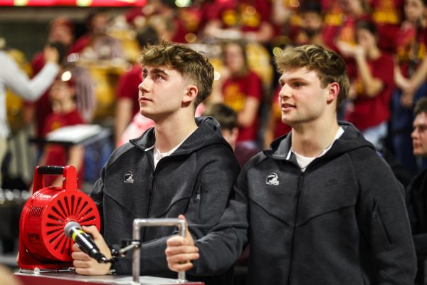 Football players Kyle Konrardy (97) and Aiden Flora (21) getting ready to turn siren, Iowa State University vs. University of West Virginia wrestling meet, Feb. 13, 2026, Hilton Coliseum, Ames, Iowa.
