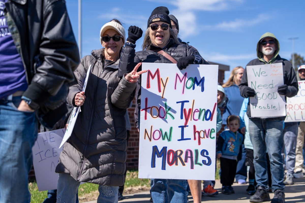 A demonstrator holds a sign reading "My mom took Tylenol now I have morals" during the No Kings protest held at O’Neil Park in Ames, Iowa, March 28, 2026.